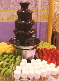 a table topped with lots of different types of candies next to a chocolate fountain