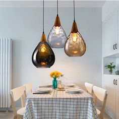 three hanging lights over a dining table in a kitchen