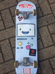 a skateboard with stickers on it is laying on the ground next to bricks