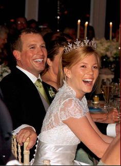 a bride and groom smile as they sit at a dinner table with candles in the background