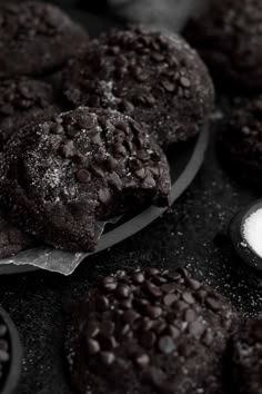 chocolate cookies with powdered sugar on top and spoons next to them in black and white