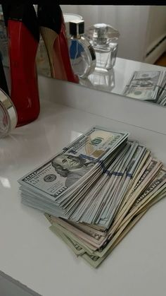 a stack of money sitting on top of a counter next to a pair of red shoes