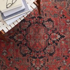 a red rug with black and grey designs on it, next to a pair of reading glasses