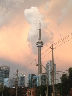 the sky is pink and cloudy as clouds loom in the distance behind some tall buildings