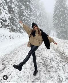 a woman in black boots and a tan jacket is skating on the snow covered road