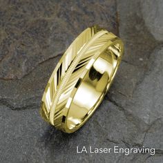 a rose gold wedding ring with an arrow in the center on a stone background that says la laser engraving