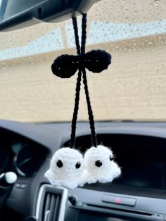 two small white owls hanging from the dash of a car