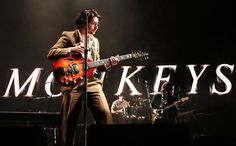 a man standing on stage with a guitar in front of him and the words motleys behind him