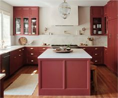 a kitchen with red cabinets and white counter tops