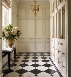 a vase with flowers sitting on top of a black and white checkerboard floor