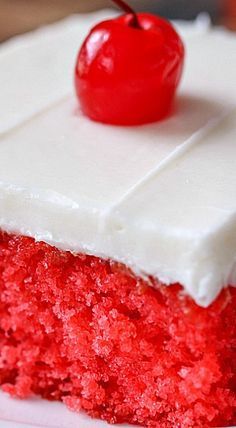 a piece of red velvet cake with white frosting and a cherry on the top