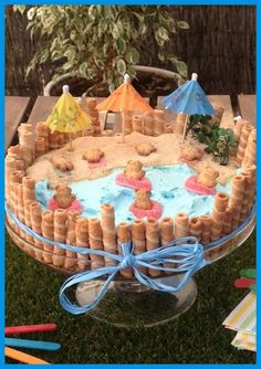 a cake that has been decorated with sand and umbrellas on the grass in front of it