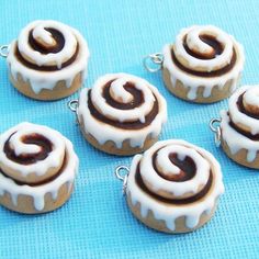 six miniature donuts with icing on them sitting on a blue tableclothed surface