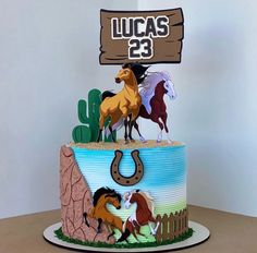 a birthday cake with horses on it and a wooden sign that says lucas'23