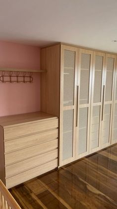 an empty room with wooden floors and cabinets in the corner, next to a stair case