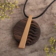 a necklace with a wooden pendant hanging from it's side on a stone surface