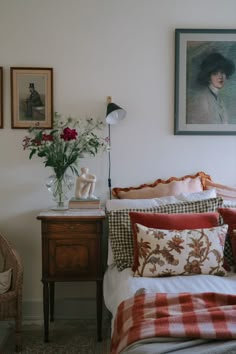 a bed with red and white pillows on top of it next to a wooden table