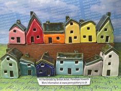 a group of small ceramic houses sitting on top of a green table next to a blue sky