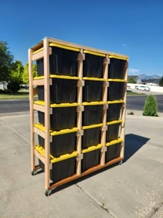 a wooden shelf with plastic bins on it in the middle of a parking lot