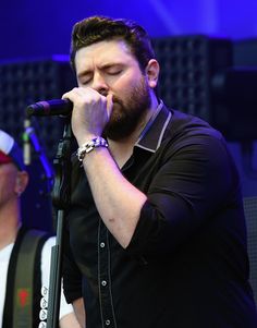 a man singing into a microphone while standing next to another man with his eyes closed