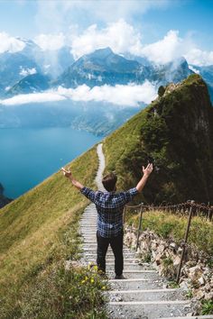 a man standing at the top of a mountain with his arms in the air and hands out