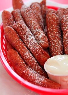 powdered sugar coated sausage sticks in a red basket with dip on the side, ready to be eaten