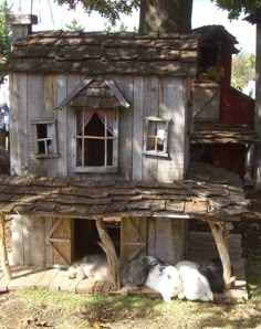 two rabbits are sleeping in front of a house made out of wood planks and logs