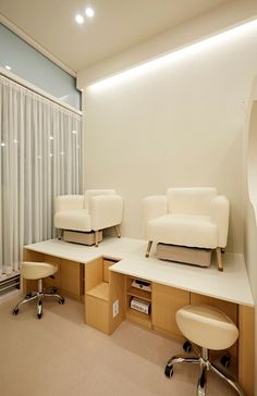 a room with two white chairs and a desk in the middle is lit by recessed lights