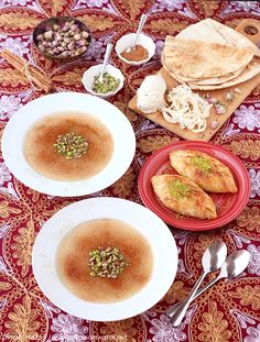 two bowls filled with food on top of a red and white table cloth next to silverware