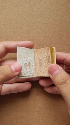 two hands holding a small piece of paper in front of a cardboard box with a heart on it