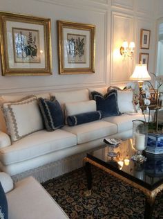 a living room with couches, tables and two framed pictures on the wall above them