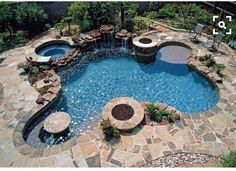 an outdoor swimming pool surrounded by stone steps and seating around the edge with fire pit on each side