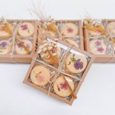 four cookies in a box with dried flowers on them