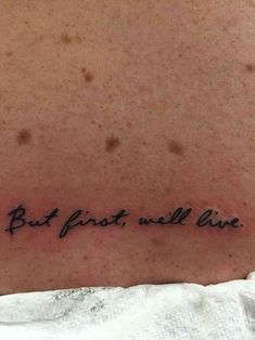 the back of a person's neck with a tattoo saying, but first we all live