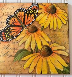 two yellow flowers with butterflies on them sitting on a piece of paper that has writing underneath it