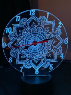 a clock that is lit up in the dark with blue numbers and designs on it