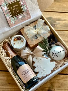 a wine bottle and some cookies in a box on a wooden table next to a christmas ornament