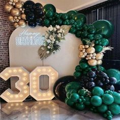 the balloon arch is decorated with balloons and streamers to celebrate 30th birthday, surrounded by greenery