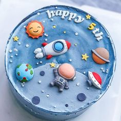 a blue birthday cake with an astronaut theme on it's icing and decorations