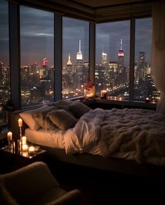 a bedroom with a view of the city lights and candles lit up on the bed