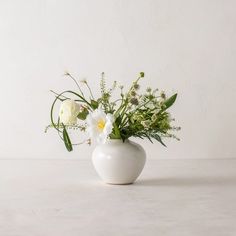 a white vase filled with flowers on top of a table