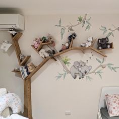 a baby's room with stuffed animals on the tree branch wall decal and crib bedding