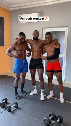 three men standing in a gym with their arms around each other and one man wearing red shorts