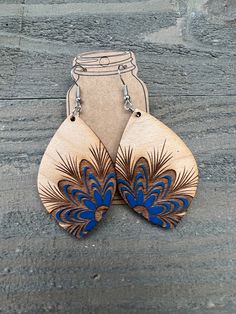 two wooden earrings with blue and brown designs on them