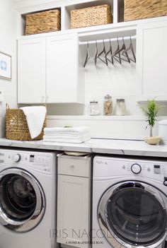 a washer and dryer in a white laundry room with baskets on the wall