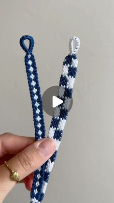 someone is holding up two blue and white bracelets with one knot in the middle