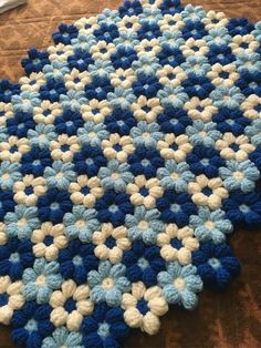 a blue and white crocheted blanket laying on the floor