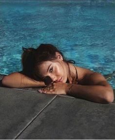 a woman laying on the edge of a swimming pool