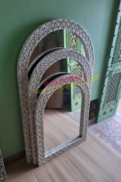 three mirrors sitting next to each other on top of a wooden floor in front of a green wall