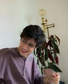 a person sitting at a table with a potted plant in front of them and a vase on the side